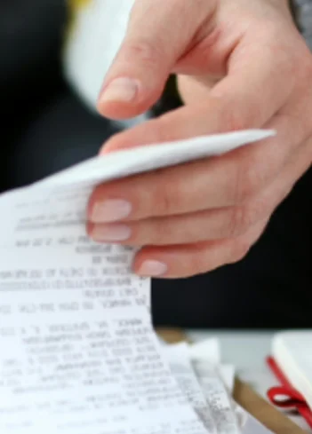 Persona revisando un recibo junto a una calculadora